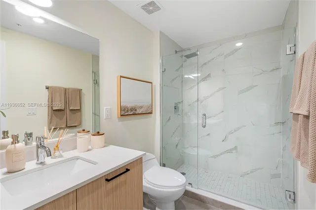 a bathroom with a sink toilet vanity and shower
