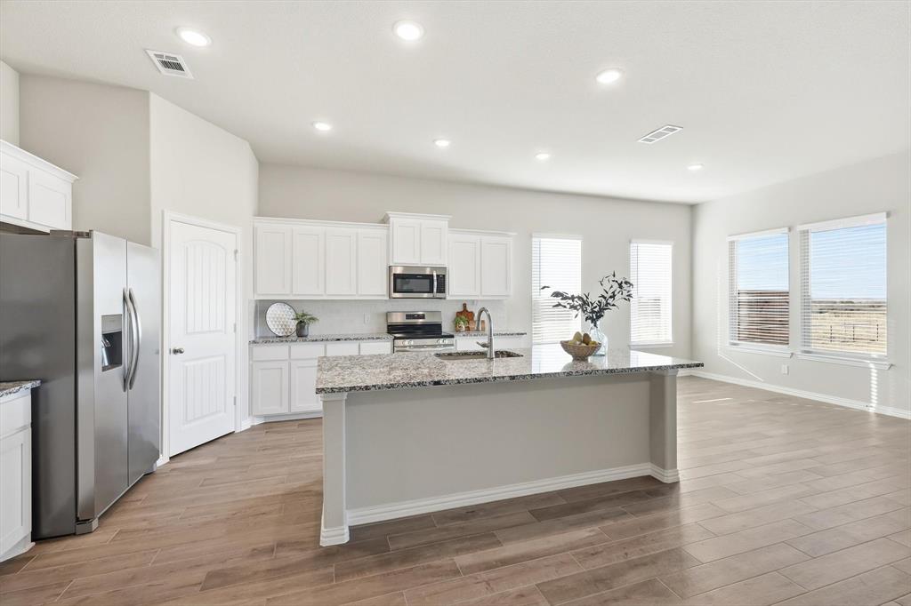 139 Steppes Court Decatur, TX 76234 - Photo 21 of 40 a kitchen with stainless steel appliances granite countertop a refrigerator a sink dishwasher a stove and white cabinets with wooden floor