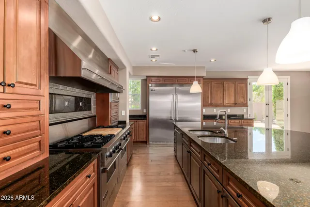 a kitchen with stainless steel appliances granite countertop a stove top oven a refrigerator a sink and a stove