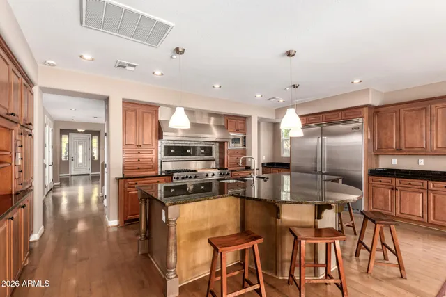 a kitchen with stainless steel appliances kitchen island granite countertop a refrigerator and cabinets