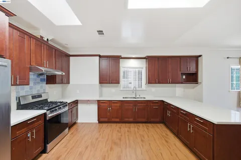 a kitchen with stainless steel appliances sink a stove and cabinets