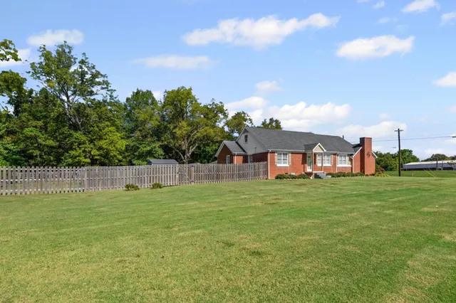 a view of a big house with a big yard and a large tree
