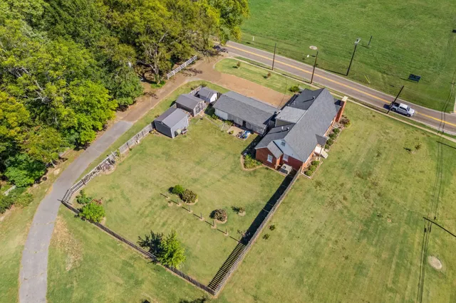 an aerial view of a swimming pool with a yard and trees