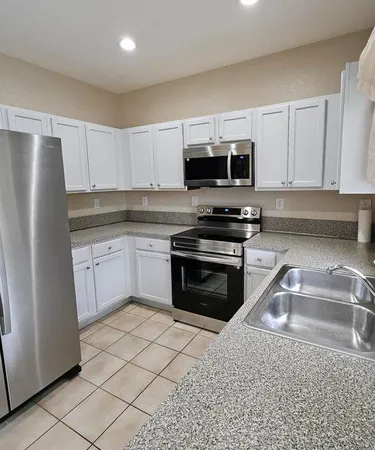 a kitchen with granite countertop a refrigerator stove and microwave