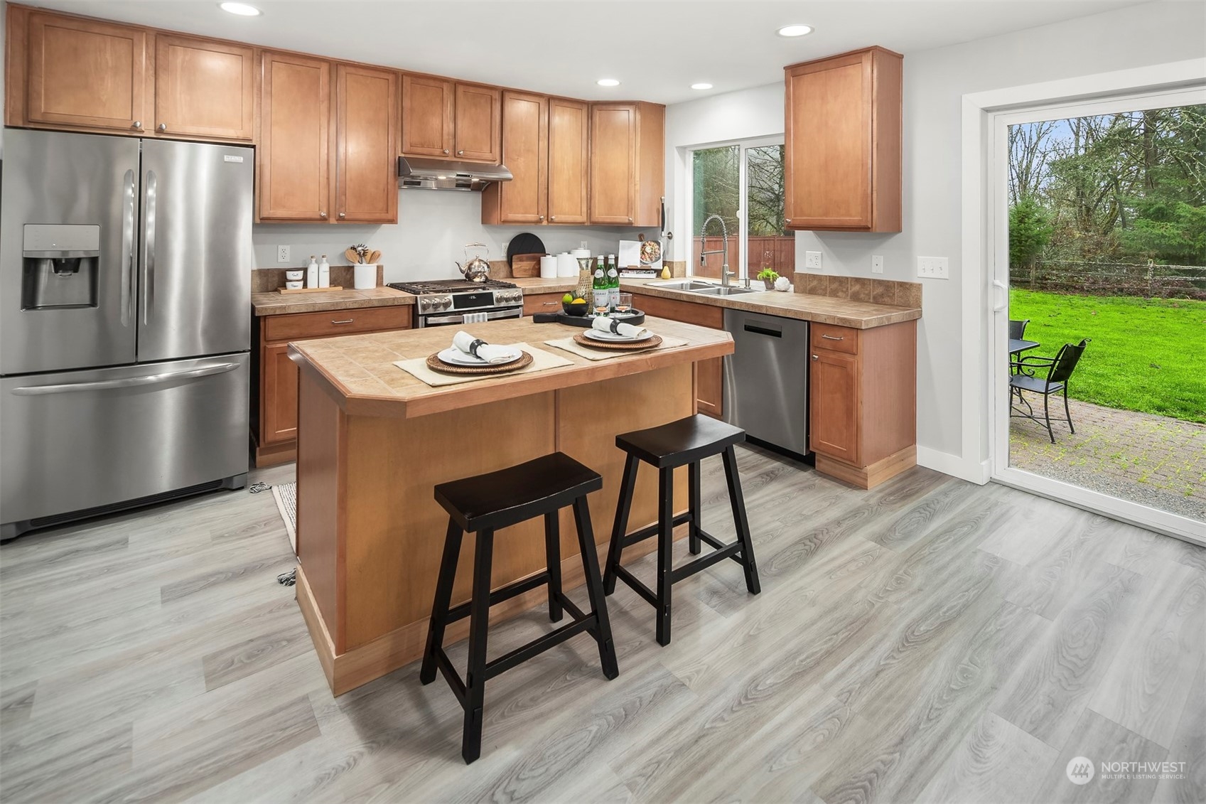 3205 Southeast 4th Street Renton, WA 98056 - Photo 8 of 38 a kitchen with stainless steel appliances kitchen island hardwood floor sink stove dining table and chairs