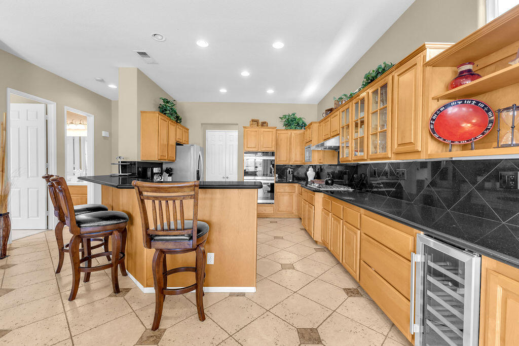 78079 Calle Norte La Quinta, CA 92253 - Photo 18 of 51 a kitchen with stainless steel appliances kitchen island granite countertop a stove a sink and a microwave