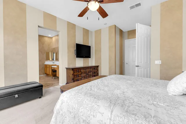 a spacious bedroom with a bed and a flat screen tv