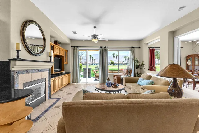 a living room with furniture a fireplace a chandelier and windows