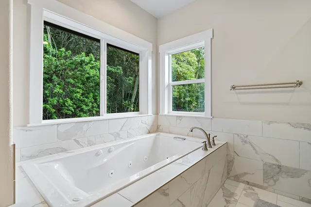 a white bath tub sitting in a bathroom next to a window