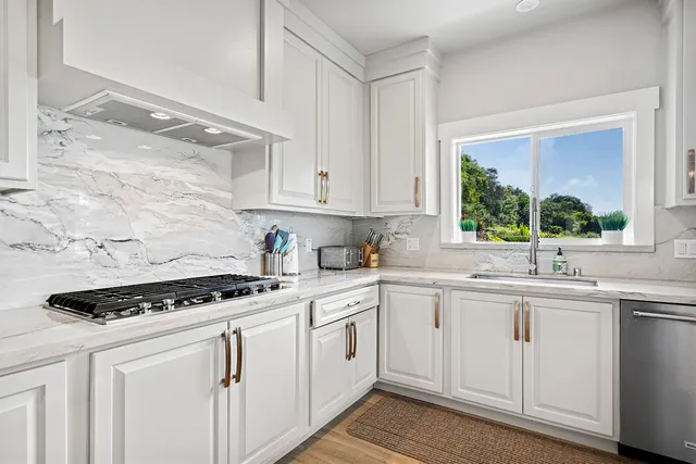 a kitchen with white cabinets sink and stove