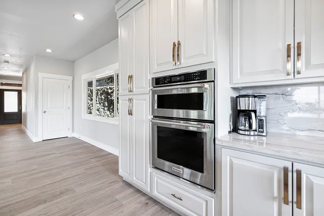 a kitchen with stainless steel appliances granite countertop a stove a microwave and a white cabinets