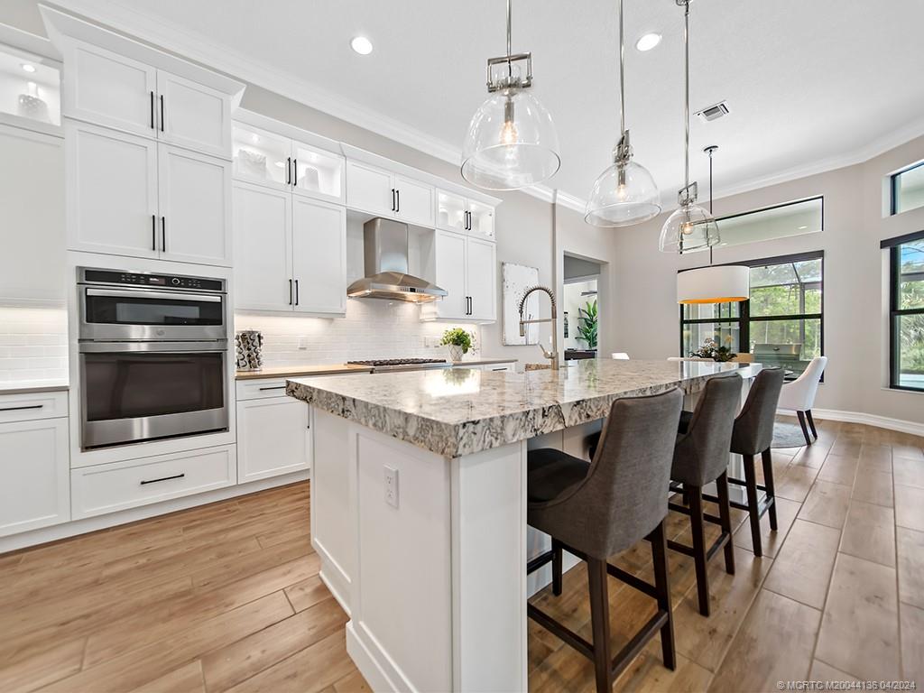 3246 Southwest Loriope Loop Palm City, FL 34990 - Photo 11 of 37 a kitchen with stainless steel appliances granite countertop a kitchen island a stove a table and chairs in it