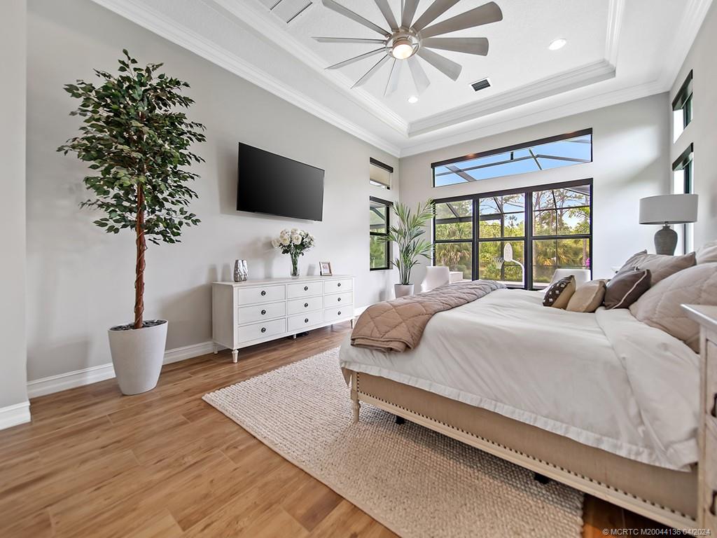 3246 Southwest Loriope Loop Palm City, FL 34990 - Photo 16 of 37 a spacious bedroom with a large bed and a chandelier
