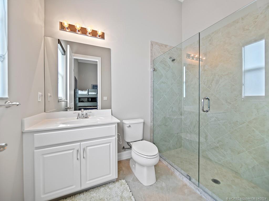 3246 Southwest Loriope Loop Palm City, FL 34990 - Photo 21 of 37 a bathroom with a toilet sink vanity and shower