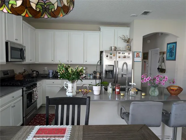 a kitchen with stainless steel appliances kitchen island granite countertop a table chairs in it and white cabinets