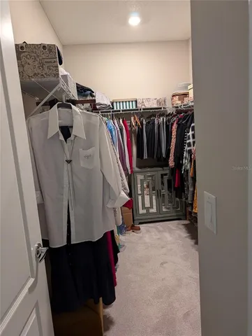 a view of walk in closet with clothes and shoes