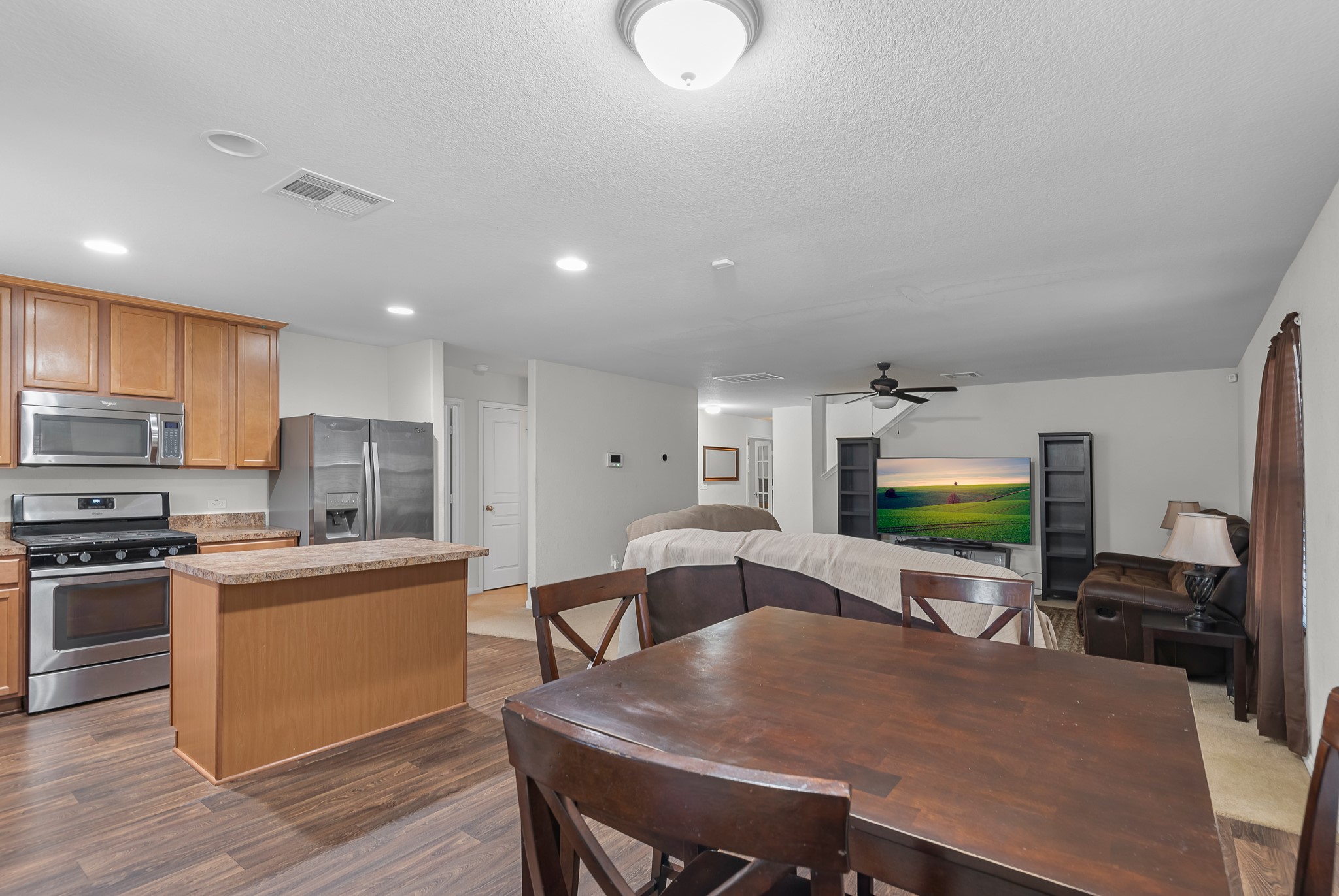1614 Perennial Lane Rosenberg, TX 77471 - Photo 13 of 34 a kitchen with stainless steel appliances granite countertop a stove top oven a sink dishwasher a dining table and chairs with wooden floor