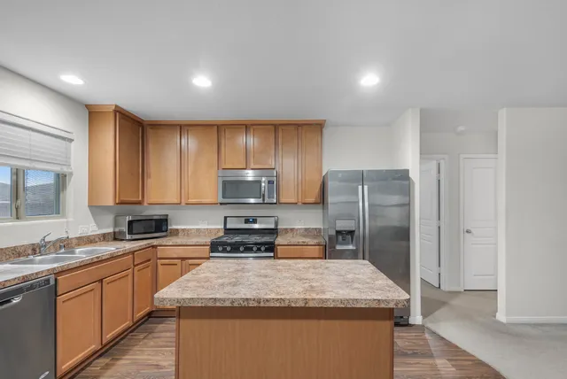 a kitchen with stainless steel appliances granite countertop a sink a stove a refrigerator a center island and cabinets