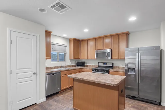 a kitchen with a sink a counter top space stainless steel appliances and cabinets