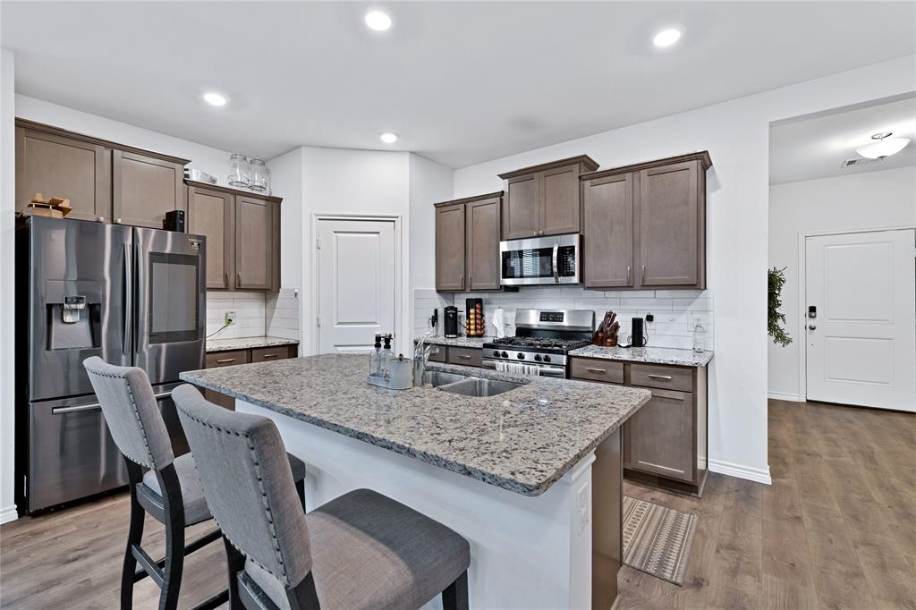 717 Rawhide Way Princeton, TX 75407 - Photo 7 of 31 a kitchen with stainless steel appliances granite countertop a stove a refrigerator a sink a stove a dining table and chairs