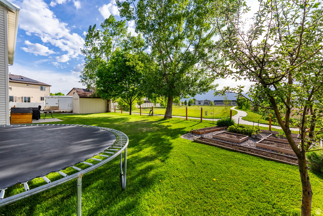2485 South 1100th Street West Logan, UT 84321 - Photo 40 of 53 Expansive backyard featuring a manicured lawn, established trees, and multiple raised garden beds