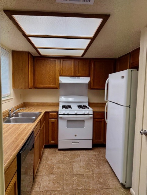 9006 B Sedgemoor Trail Austin, TX 78748 - Photo 7 of 16 Kitchen featuring white appliances, light countertops, stone finish floors, a textured ceiling, and under cabinet range hood