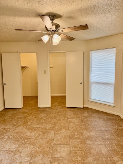9006 B Sedgemoor Trail Austin, TX 78748 - Photo 9 of 16 Unfurnished bedroom featuring a walk in closet, a textured ceiling, and a ceiling fan