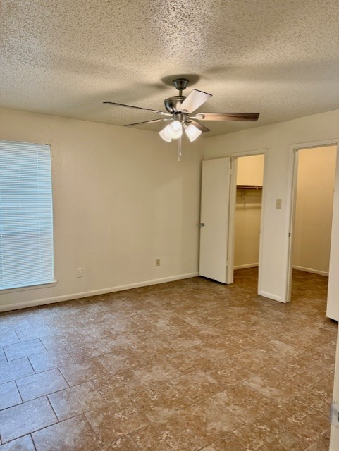 9006 B Sedgemoor Trail Austin, TX 78748 - Photo 10 of 16 Unfurnished bedroom featuring a walk in closet, a textured ceiling, and ceiling fan