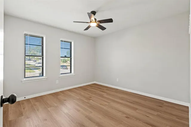 an empty room with wooden floor fan and windows