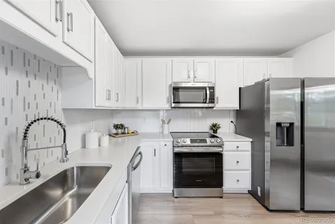 a kitchen with stainless steel appliances granite countertop a sink a stove and a refrigerator