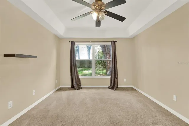 an empty room with windows and ceiling fan