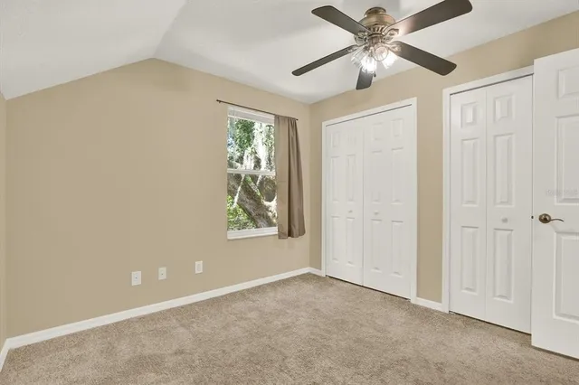 an empty room with windows and fan