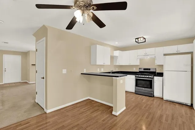 a kitchen with stainless steel appliances granite countertop a refrigerator a stove a microwave and white countertops with wooden floor