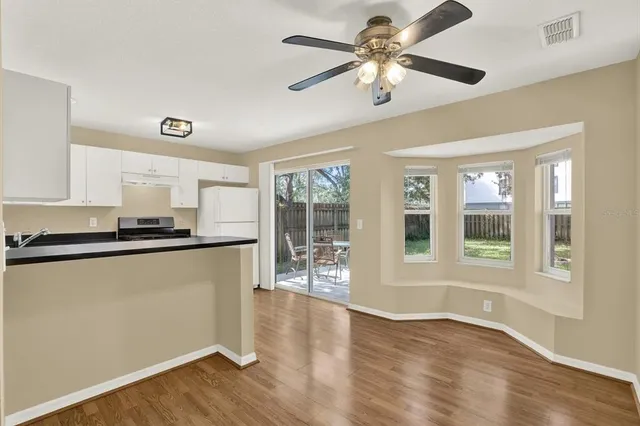 a view of a kitchen with a stove cabinets a ceiling fan and wooden floor