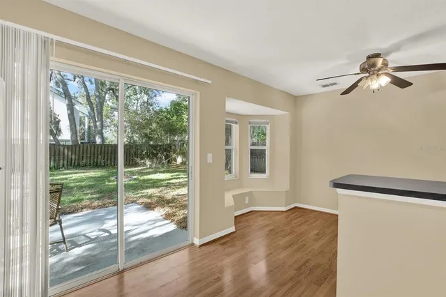 a view of empty room with wooden floor and fan