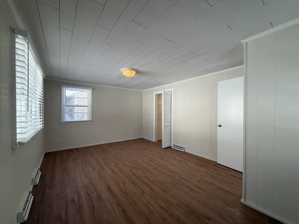 an empty room with wooden floor and windows