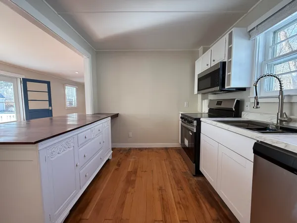a kitchen with granite countertop a sink cabinets stainless steel appliances and a window