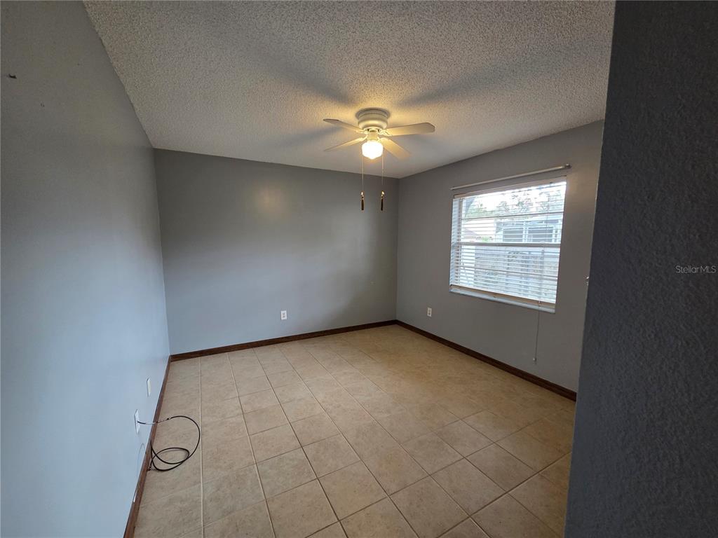 7605 Landmark Drive Spring Hill, FL 34606 - Photo 22 of 26 an empty room with windows and ceiling fan