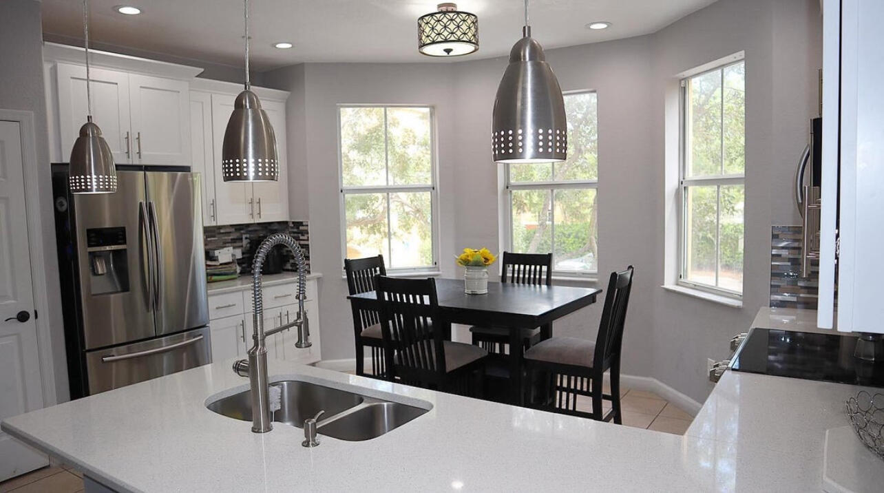 a kitchen with stainless steel appliances a dining table chairs and window