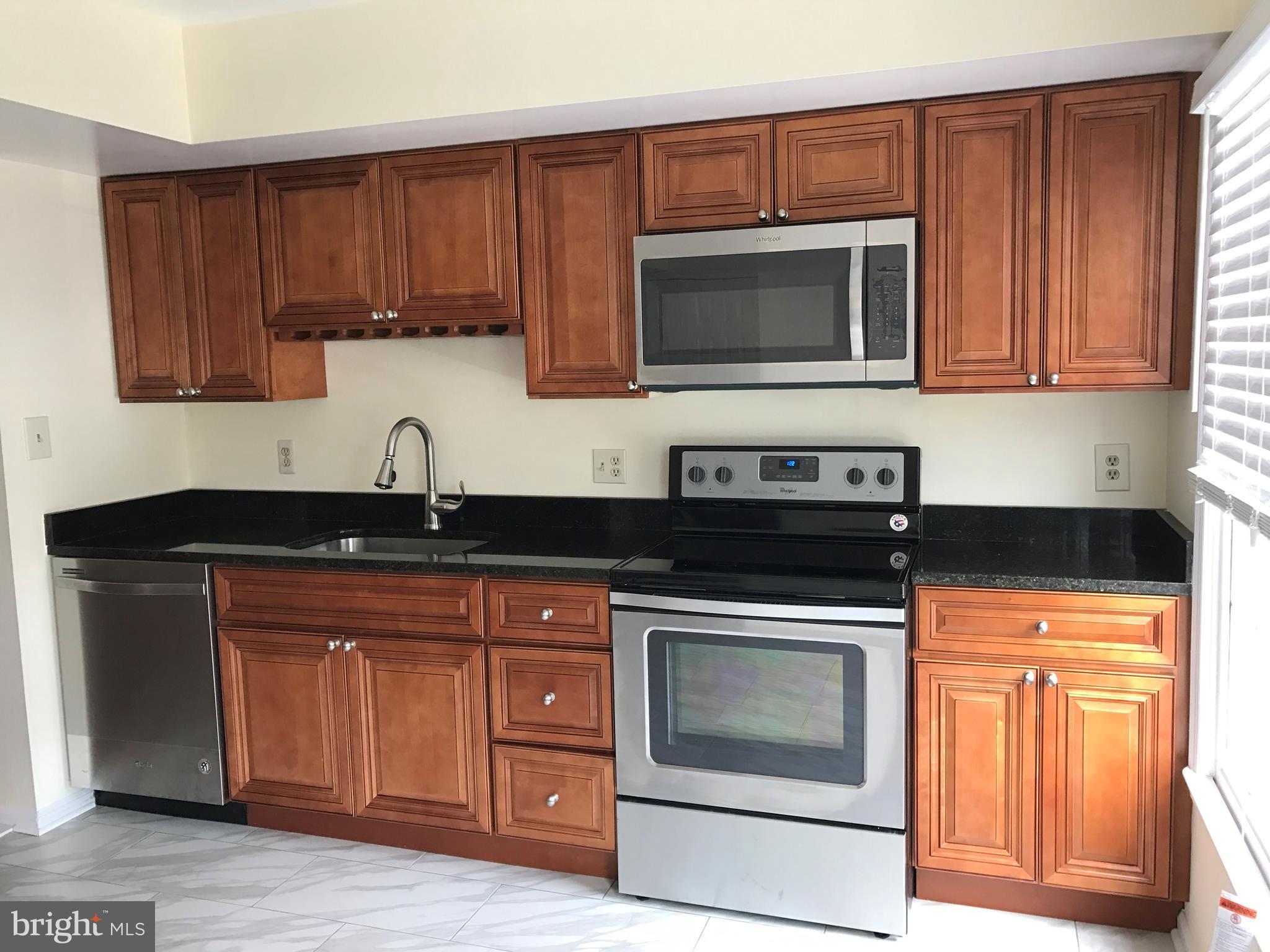 10504 Grove Ridge Place, Unit 48 Rockville, MD 20852 - Photo 5 of 30 a kitchen with granite countertop wood cabinets stainless steel appliances and a sink