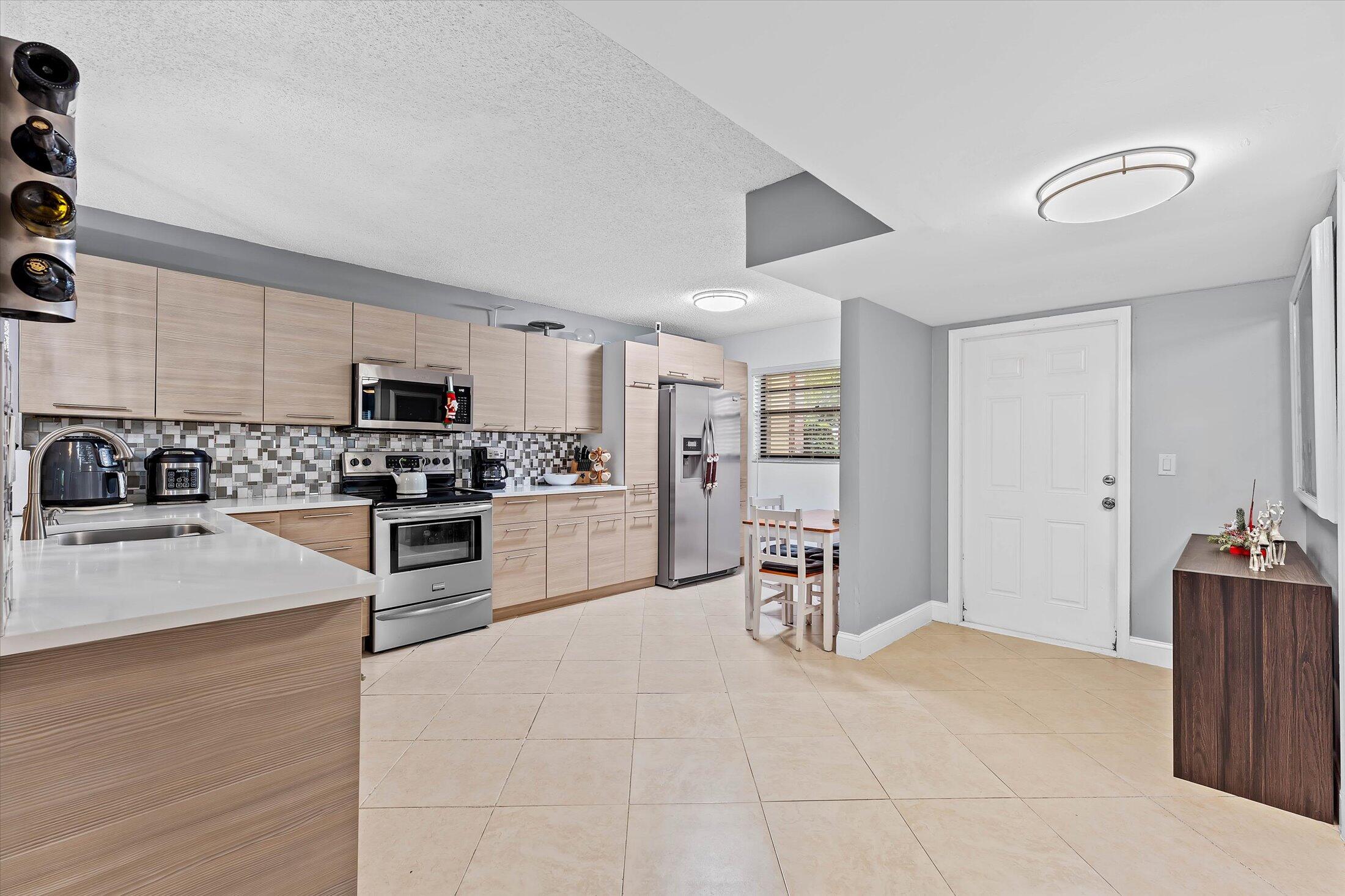 23466 Lyons Road, Unit 501 Boca Raton, FL 33428 - Photo 4 of 40 a kitchen with granite countertop a stove a sink and a refrigerator