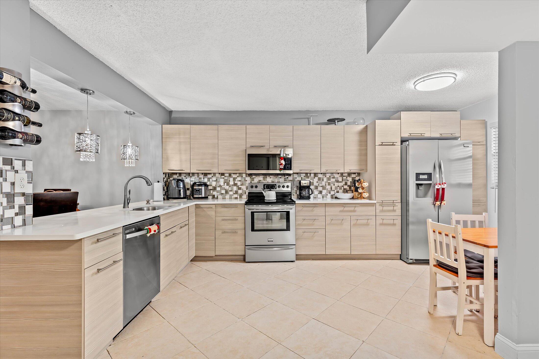 23466 Lyons Road, Unit 501 Boca Raton, FL 33428 - Photo 5 of 40 a kitchen with white cabinets and appliances