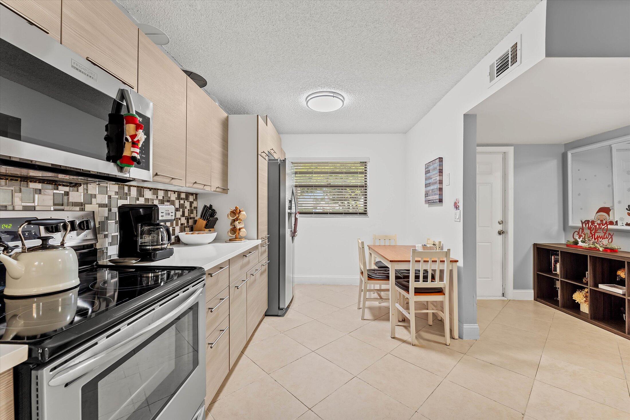 23466 Lyons Road, Unit 501 Boca Raton, FL 33428 - Photo 6 of 40 a kitchen with a stove and chairs