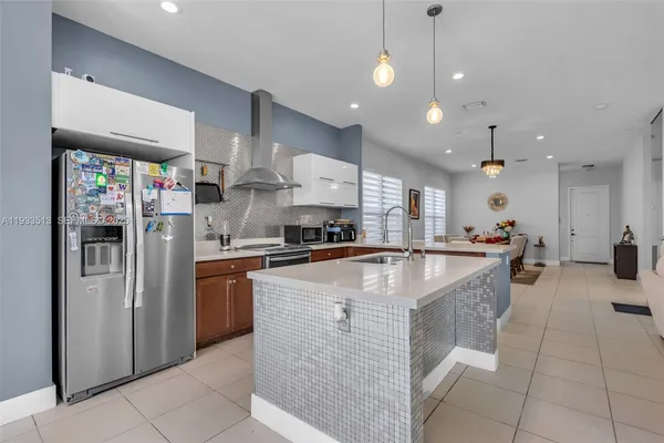 a large kitchen with stainless steel appliances granite countertop a large counter top a stove a refrigerator and a sink