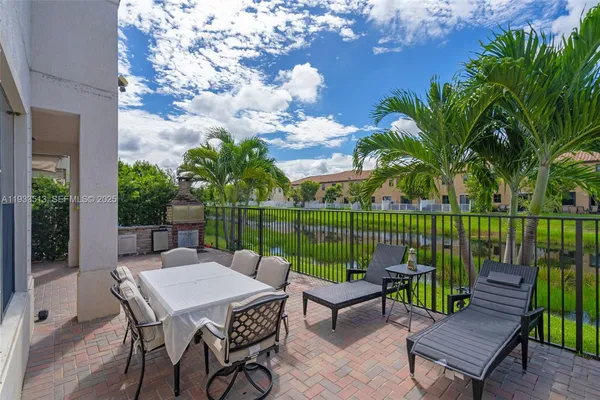 a patio with table and chairs potted plants and a palm tree