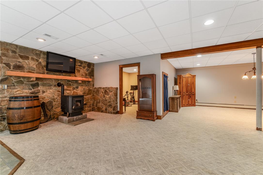 465 Raubsville Road Easton, PA 18042 - Photo 46 of 60 A spacious lower level retreat features a stone accent wall, a cozy wood stove, and soft carpet.