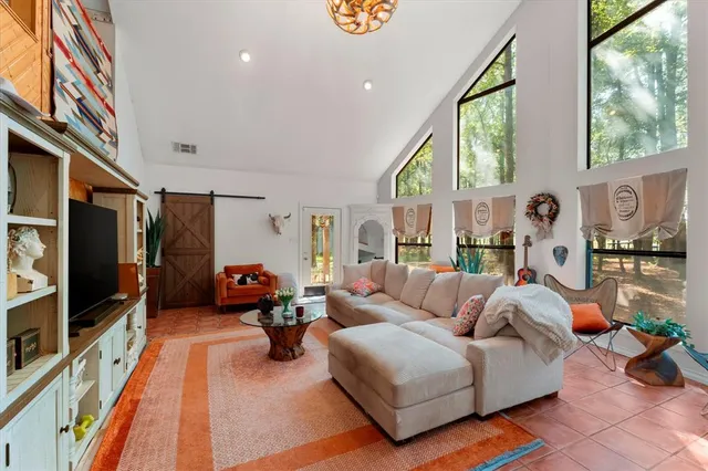 a living room with furniture a flat screen tv and a floor to ceiling window