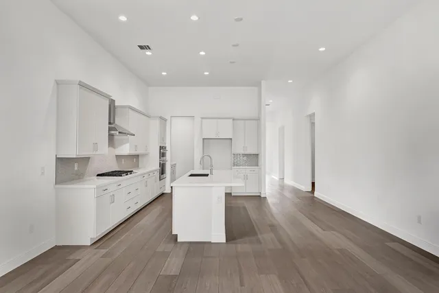 a large kitchen with a lot of counter space and wooden floor