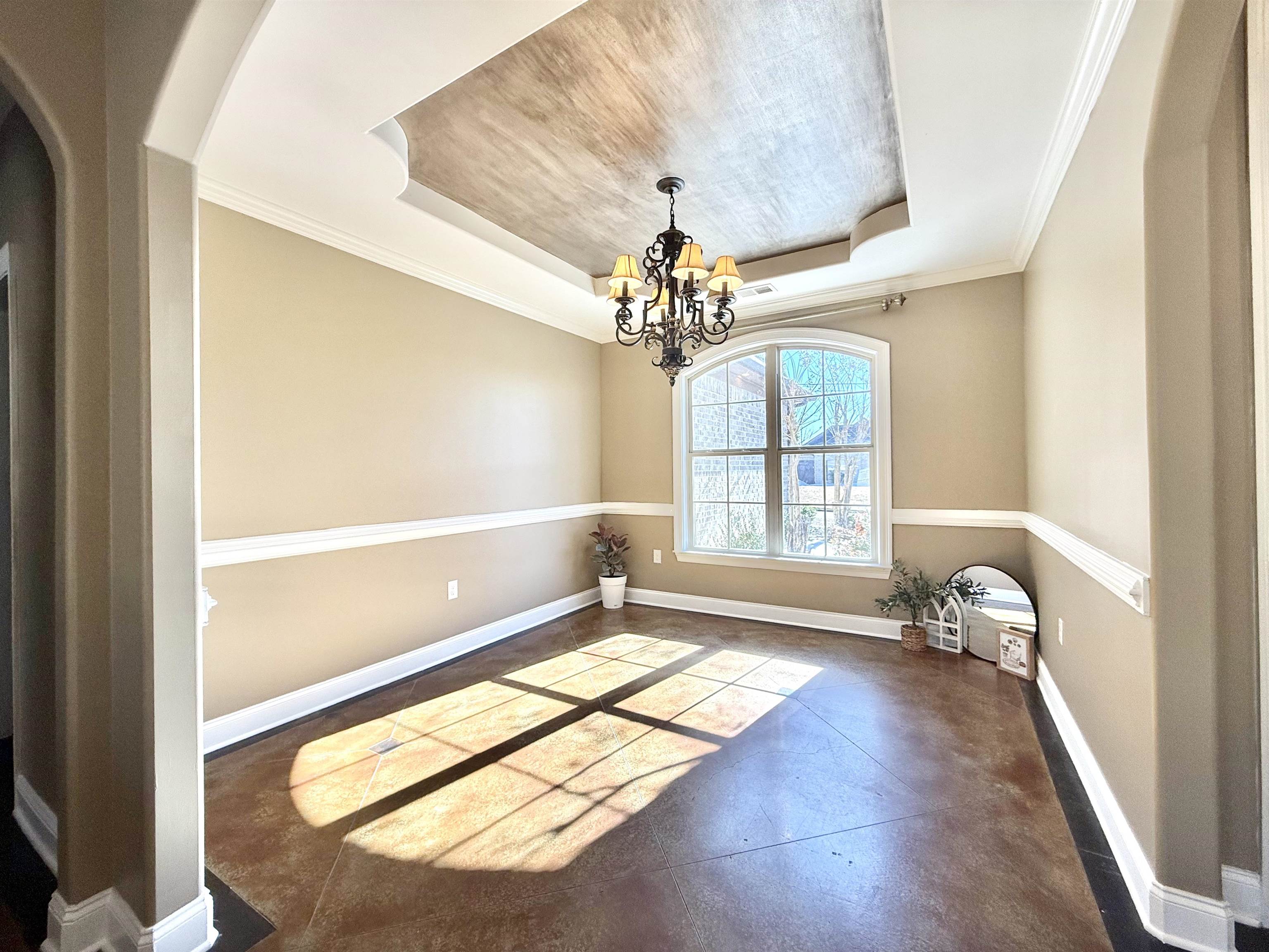 54 Palmer Cove Atoka, TN 38004 - Photo 7 of 40 Unfurnished dining area featuring arched walkways, concrete flooring, crown molding, a raised ceiling, and hanging lights