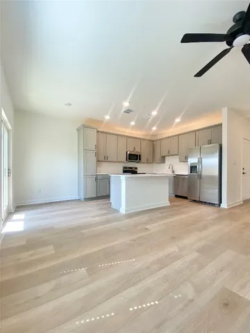 a view of kitchen with refrigerator and white cabinets